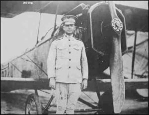 A.A. Cunningham poses next to biplane 